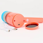 An orange handheld electric cleaning brush with a blue foam head, shown with its white USB-C charging cable and a separate orange lid on a white background.
